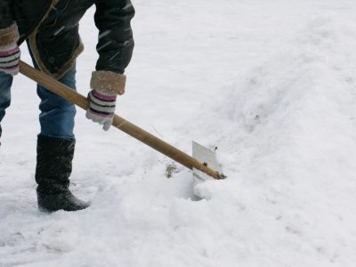 Janitor cleans snow of shovel.